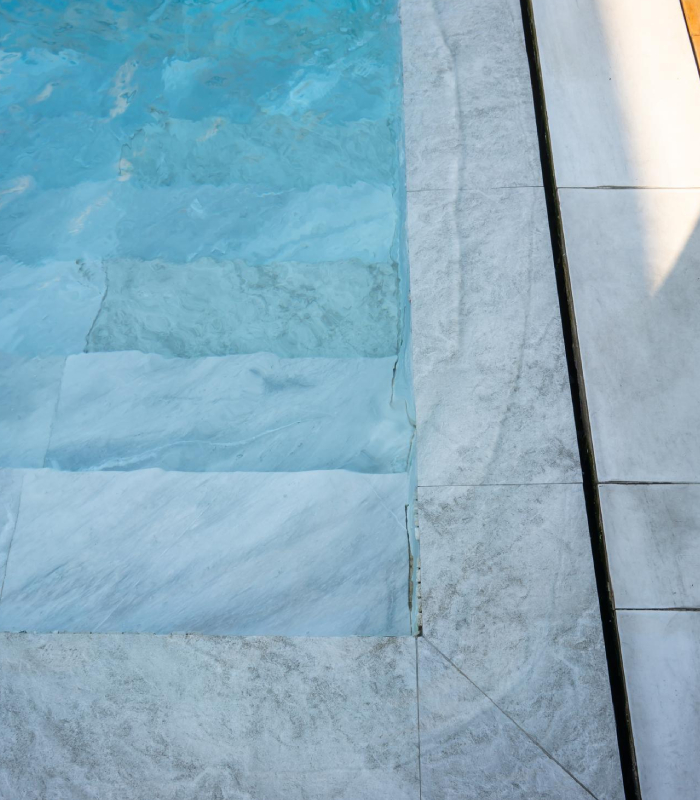 Liner armé piscine et étanchéité du bassin Liner armé de piscine bleu clair avec escalier immergé et margelles en pierre