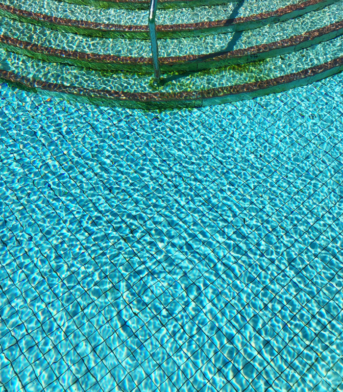 Liner armé piscine avec finition mosaïque Liner armé de piscine à motif quadrillé bleu avec escalier immergé et eau transparente